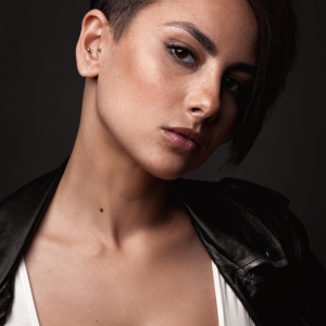 Beautiful sexy woman in a leather jacket. Portrait on a dark background