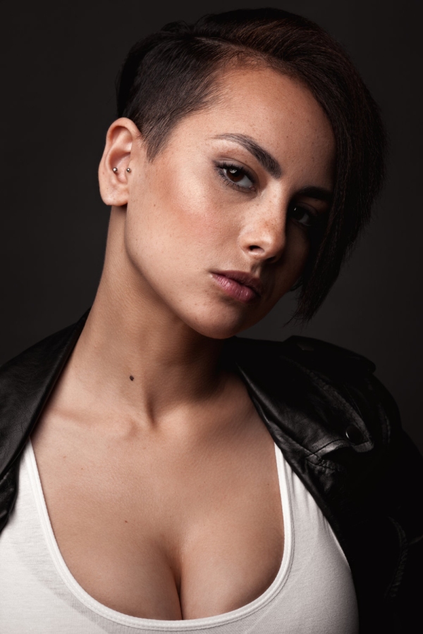 Beautiful sexy woman in a leather jacket. Portrait on a dark background