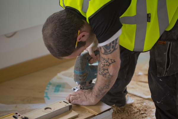 Carpenter working on skirting boards on a large building site.