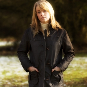 A pretty blonde girl in a leather overcoat