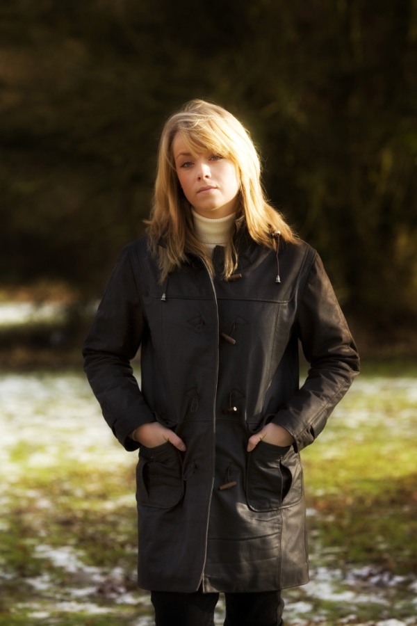 A pretty blonde girl in a leather overcoat