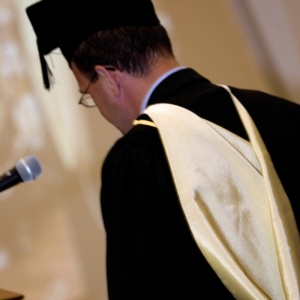 University official in full regalia on graduation day dispensing degree qualifications