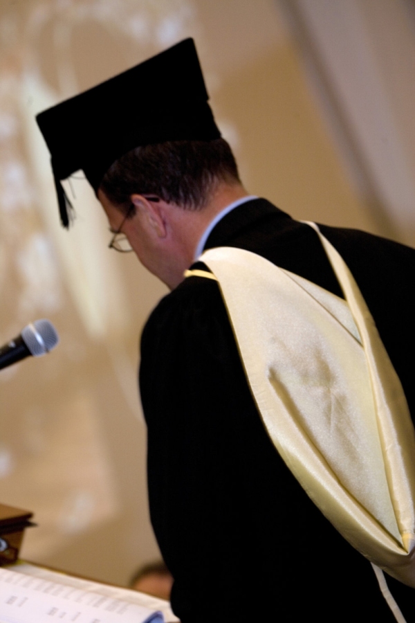 University official in full regalia on graduation day dispensing degree qualifications