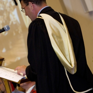 University official in full regalia on graduation day dispensing degree qualifications