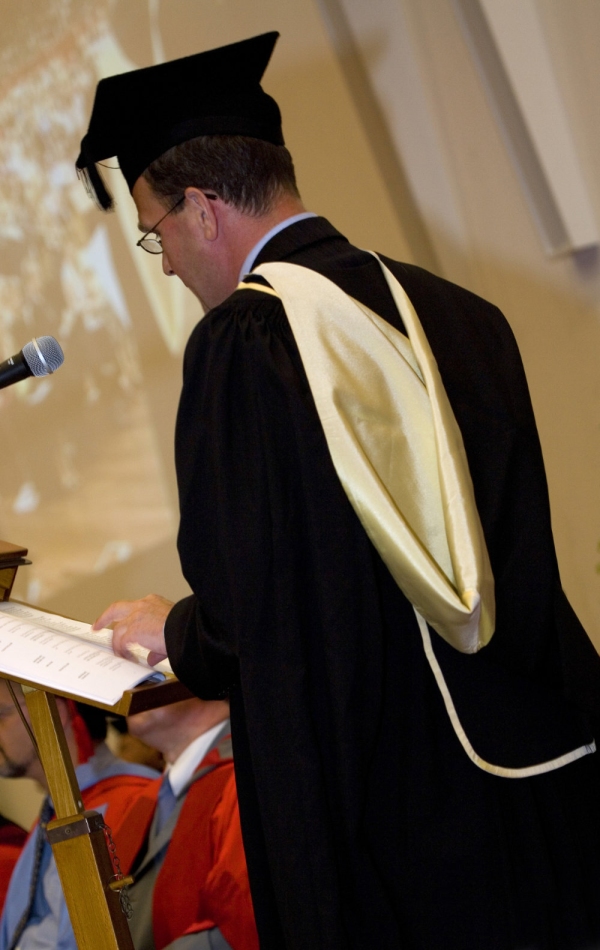 University official in full regalia on graduation day dispensing degree qualifications