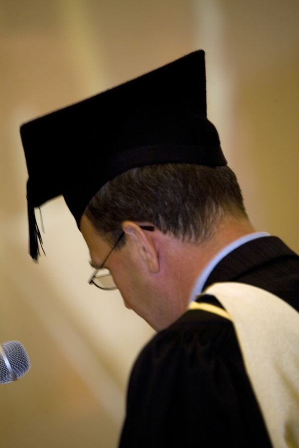 University official in full regalia on graduation day dispensing degree qualifications