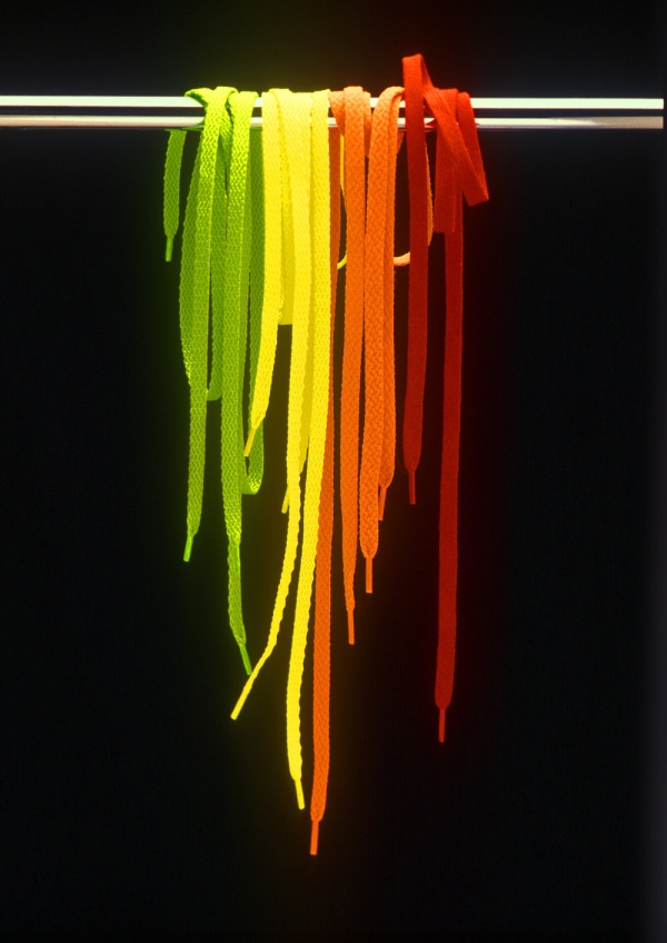 A selection of brightly coloured shoelaces on a chrome bar against a black background