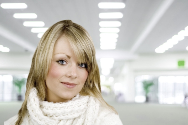 A beautiful young woman smiling at the camera with a blurred interior background