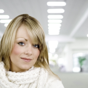 A beautiful young woman smiling at the camera with a blurred interior background