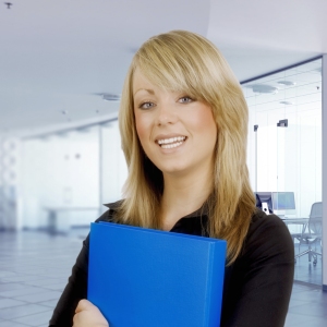 Pretty young office worker with blue folder and blurred background