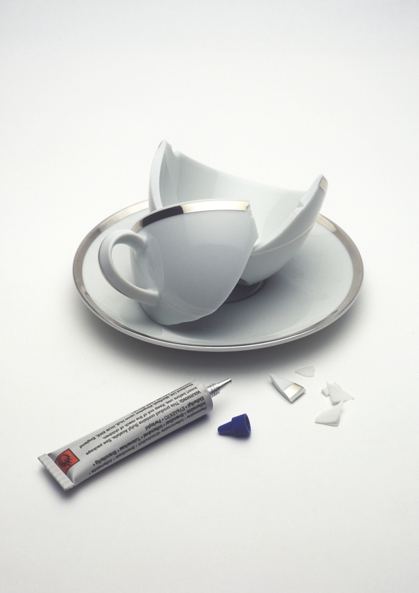 An image of an expensive but broken cup and saucer with a tube of superglue