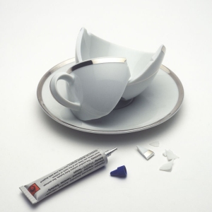 An image of an expensive but broken cup and saucer with a tube of superglue