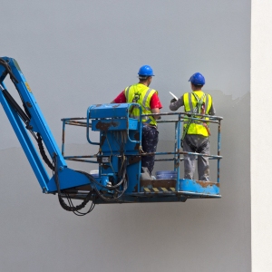 Two plasterers finishing off a wall on a lift platform