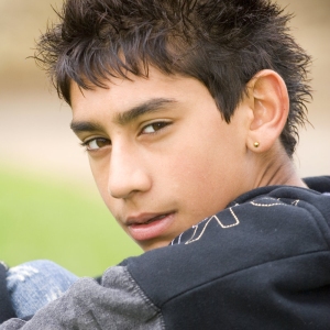 A young mixed race boy sitting and looking at the camera over his shoulder