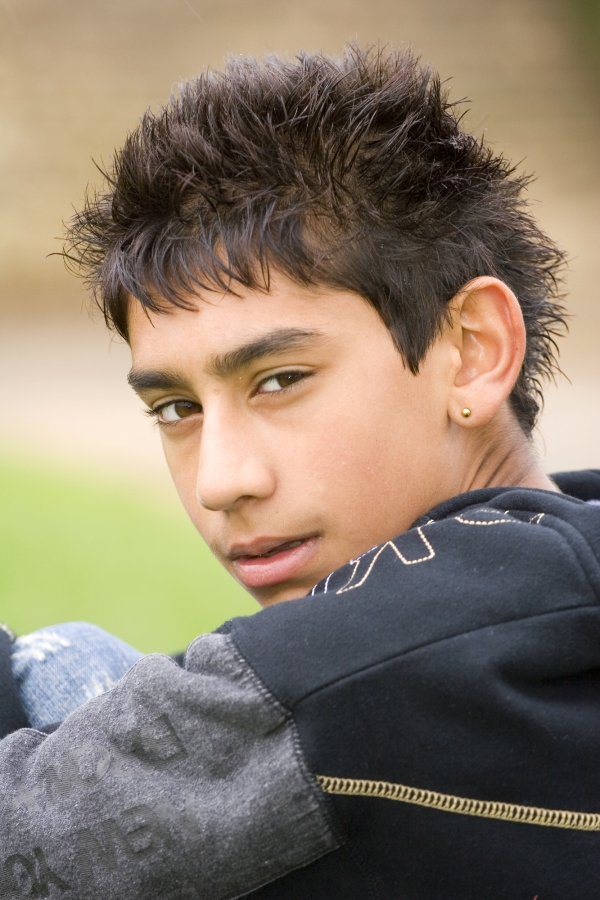 A young mixed race boy sitting and looking at the camera over his shoulder