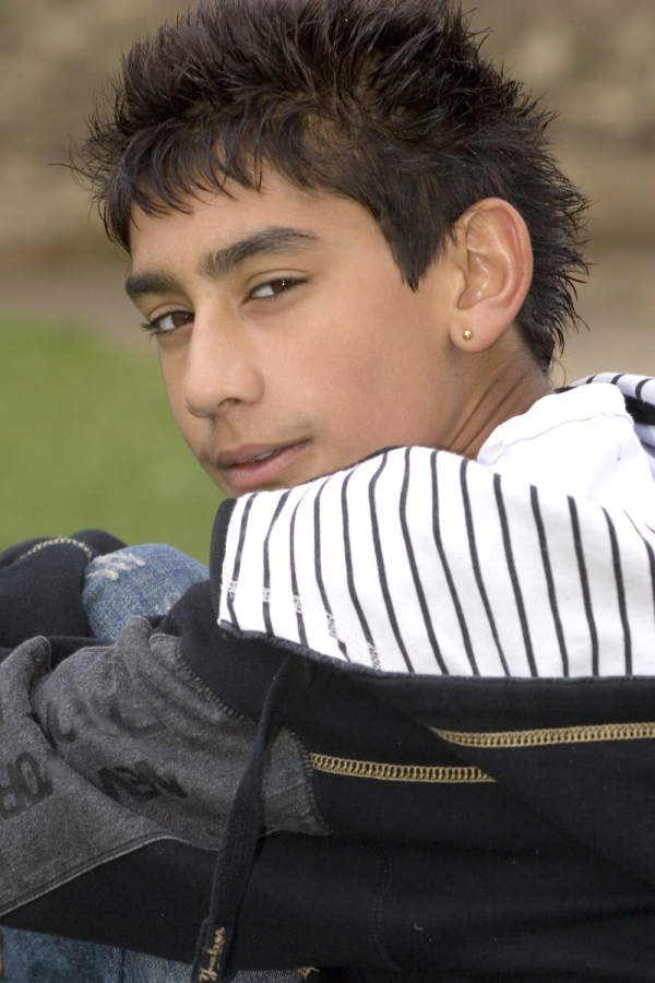 An asian or mixed race boy looking over his shoulder at the camera