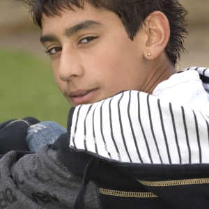 An asian or mixed race boy looking over his shoulder at the camera