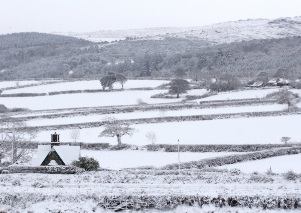 A farm house in a winter landscape with thick snow