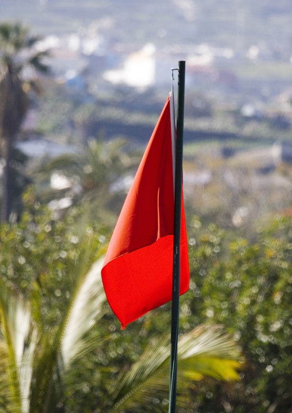 A red flag on a pole with out of focus background