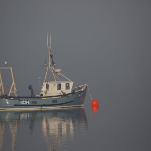 A fishing boat moored in thick fog