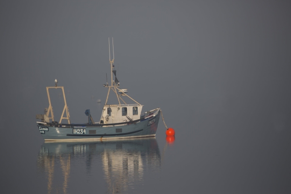 A fishing boat moored in thick fog