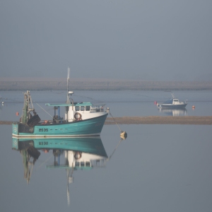 Fishing boats at anchor in the morning fog on an estuary