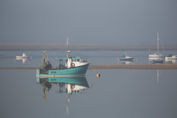 Fishing boats at anchor in the morning fog on an estuary