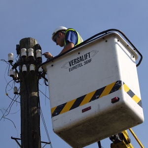 A telephone engineer repairing or service telephone or broadband connections on a telegraph pole