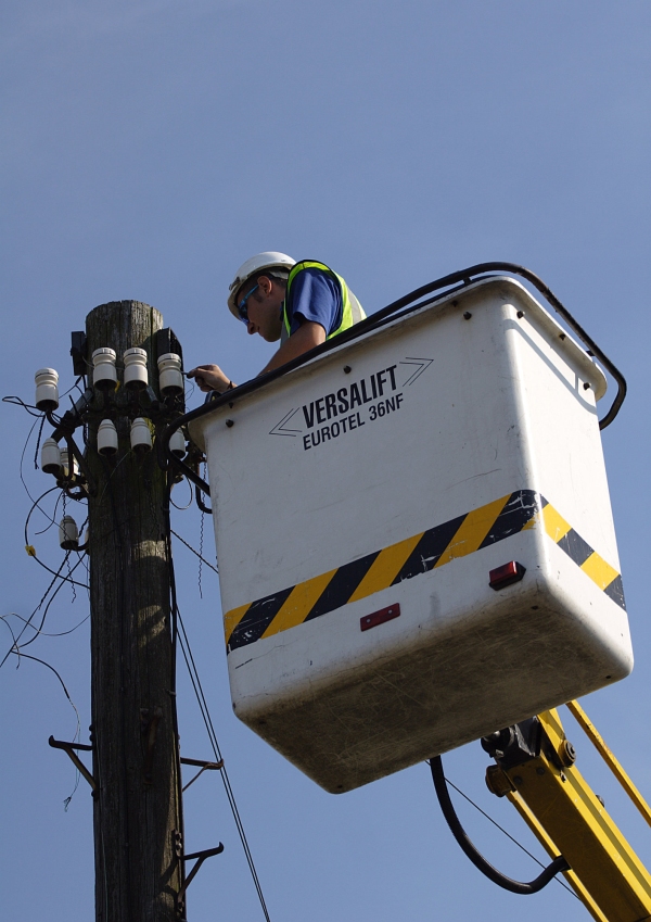 A telephone engineer repairing or service telephone or broadband connections on a telegraph pole