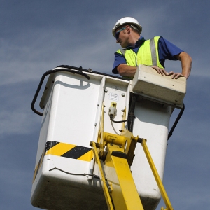 A telecoms engineer working on a telegraph pole from a lift platform or cherry picker