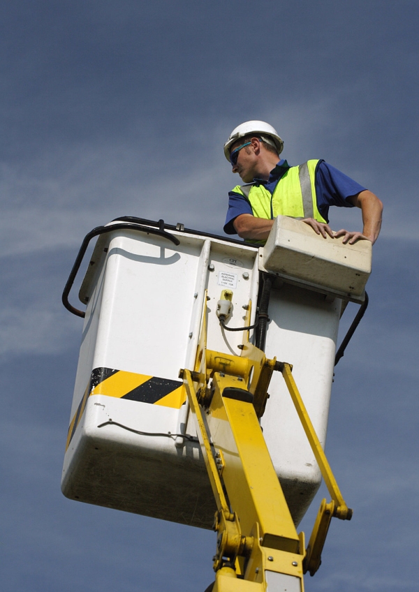 A telecoms engineer working on a telegraph pole from a lift platform or cherry picker