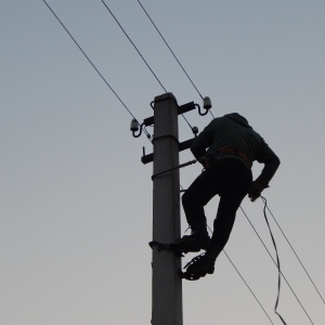 Electrician or telecommunications engineer working on a telegraph pole