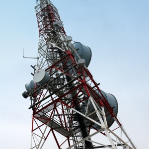 A communications mast with satellite dishes agains a blue sky