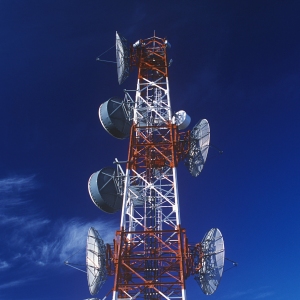 A red and white telecommunications tower against a blue sky