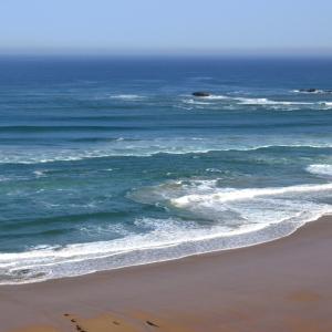 a sandy beach beside the sea under a blue sky