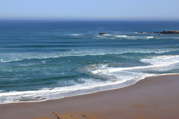 a sandy beach beside the sea under a blue sky