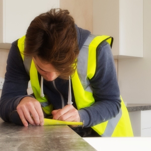 A carpenter, measuring a worktop for fitting in a new kitchen