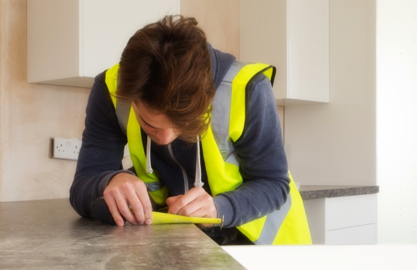 A carpenter, measuring a worktop for fitting in a new kitchen