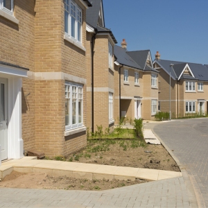 An empty street in a mostly complete new housing development, with houses sold before completion