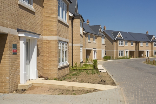 An empty street in a mostly complete new housing development, with houses sold before completion