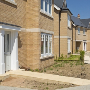 An empty street in a mostly complete new housing development, with houses sold before completion