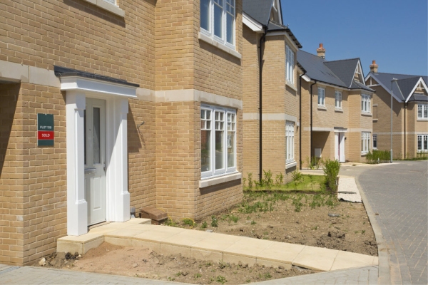 An empty street in a mostly complete new housing development, with houses sold before completion