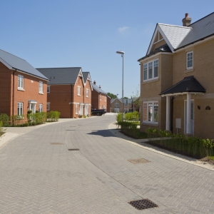 An empty street in a mostly complete new housing development, with houses sold before completion