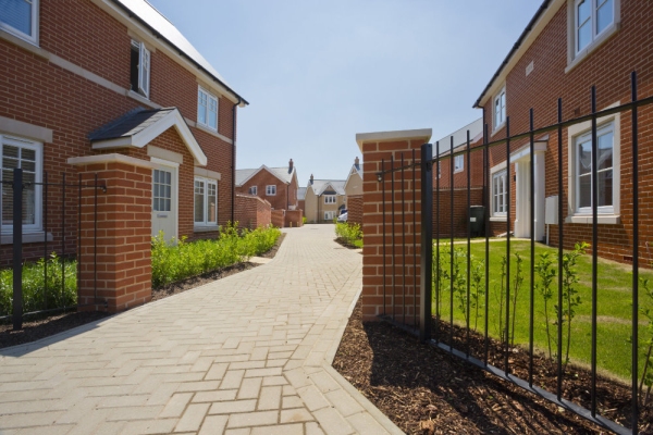 An empty street in a mostly complete new housing development, with houses sold before completion