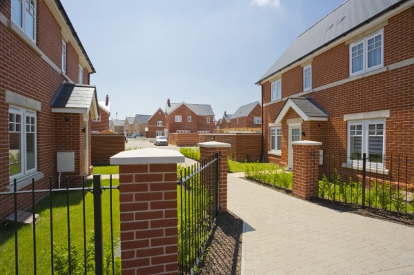 An empty street in a mostly complete new housing development, with houses sold before completion