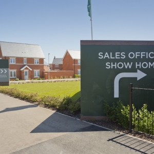 An empty street in a mostly complete new housing development, with show home and sales