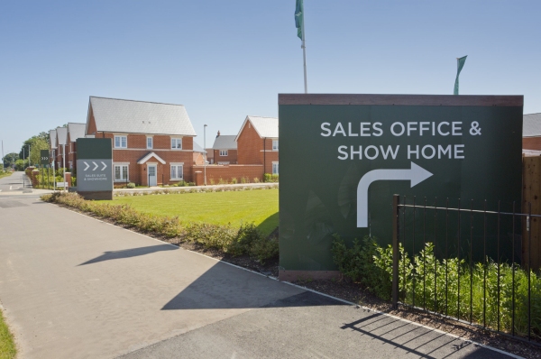 An empty street in a mostly complete new housing development, with show home and sales