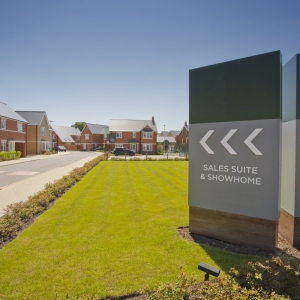 An empty street in a mostly complete new housing development, with show home and sales