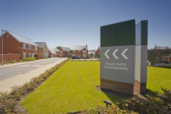 An empty street in a mostly complete new housing development, with show home and sales