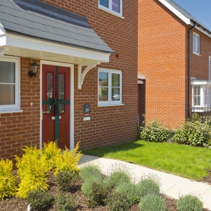 An empty street in a mostly complete new housing development, with houses sold before completion